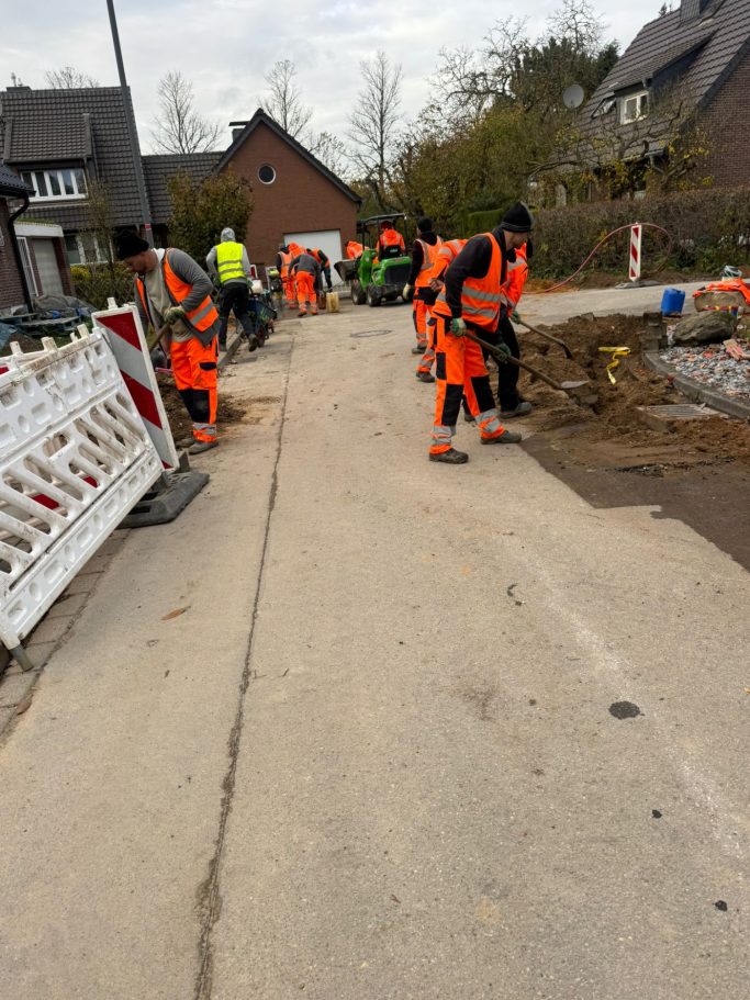 Arbeiter in oranger Sicherheitskleidung bei Straßenbauarbeiten.