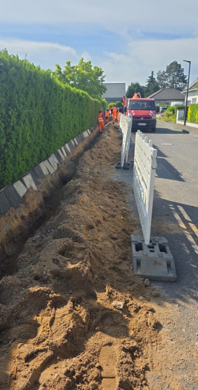 Bauarbeiten an der Straße mit einer aufgerissenen Grube und Absperrungen.