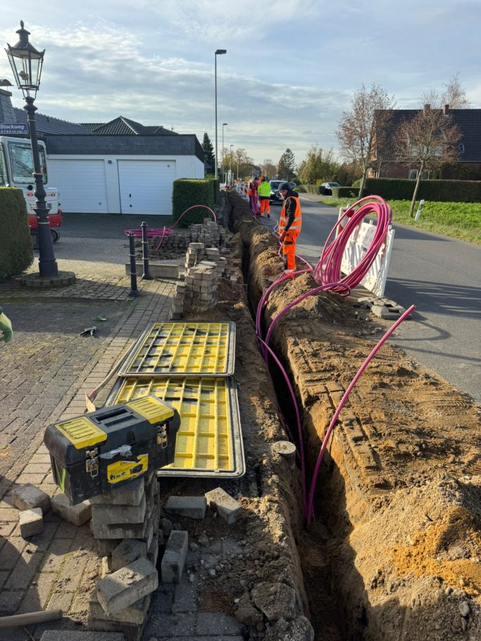 Bauarbeiten an einer Straße mit offener Grube und Bauzubehör.